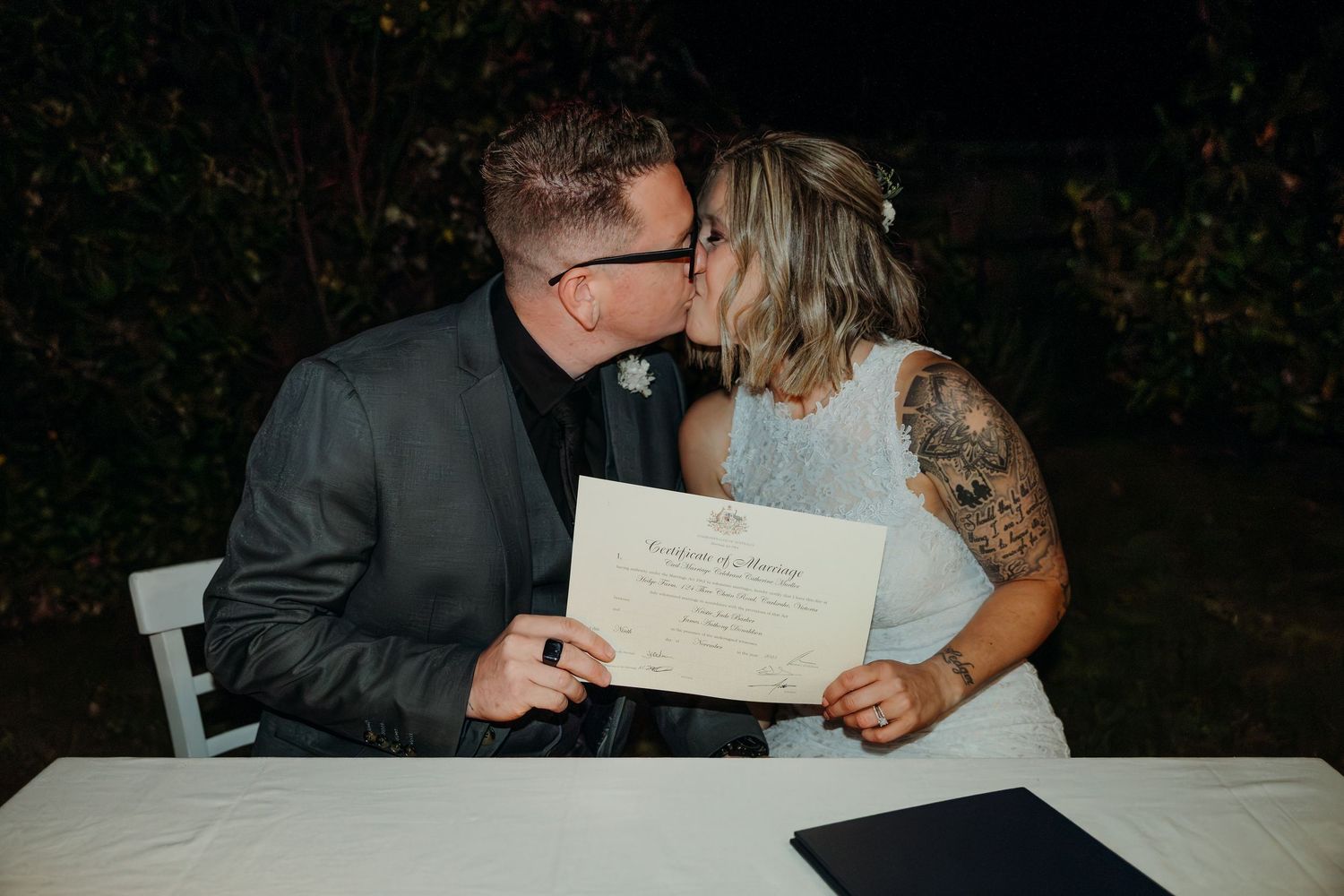 A couple sits at a table reviewing paperwork together in a dimly lit setting.
