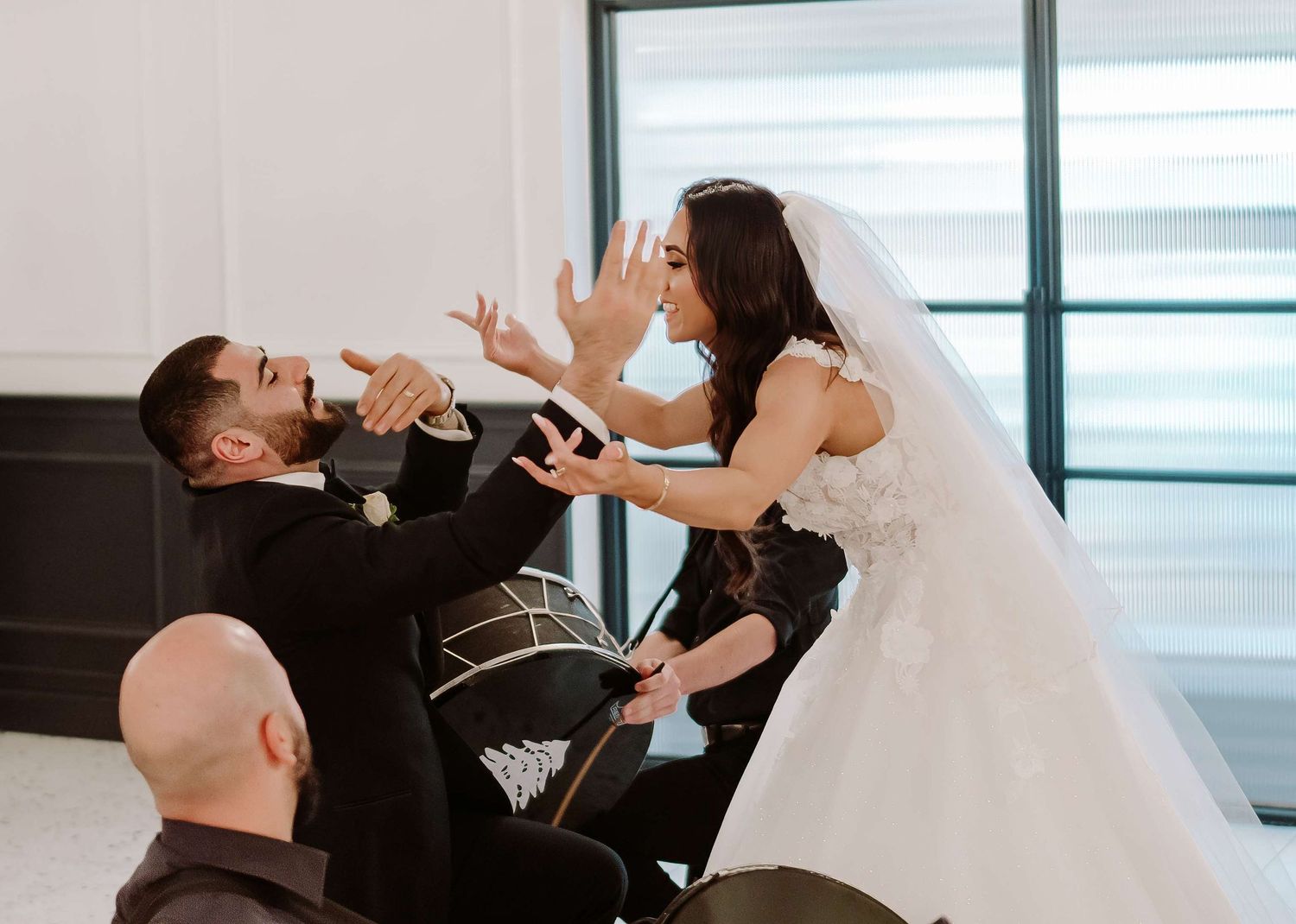 Playful moment captured at wedding reception as couple gesture dramatically in formal attire.