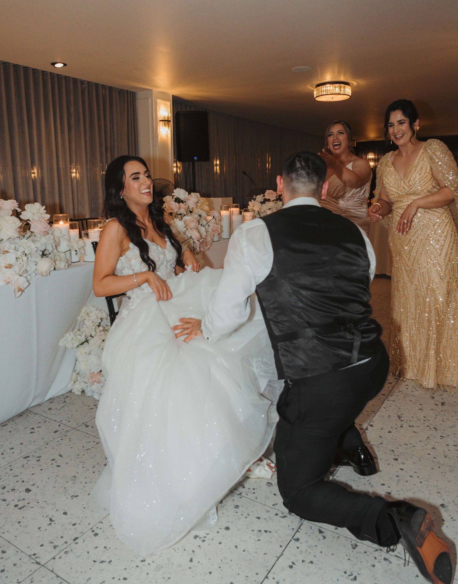 People enjoying a festive celebration with dancing on white flooring at a wedding reception with elegant décor.