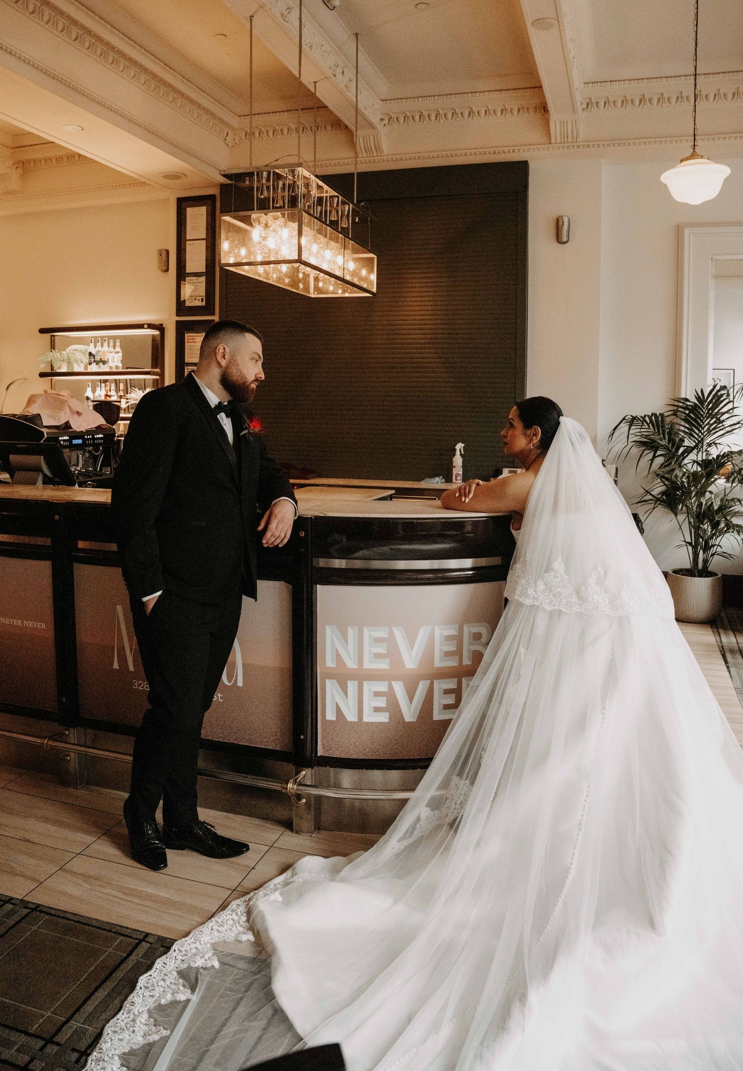 Bride and groom share a romantic moment at the Never Never bar, bride in a stunning white gown with long veil.