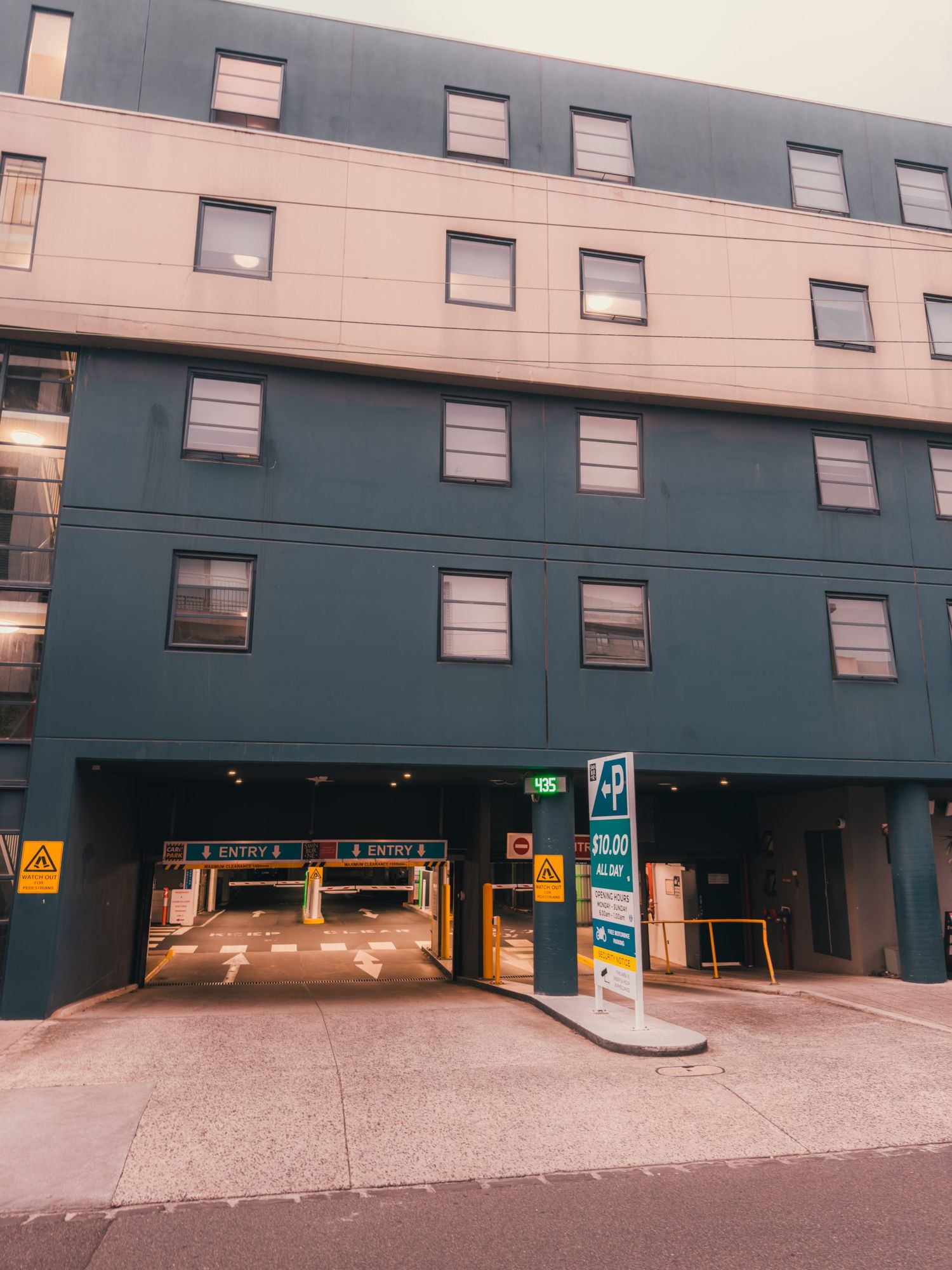 Modern building exterior with parking garage entrance and blue-gray facade with multiple windows on upper floors.
