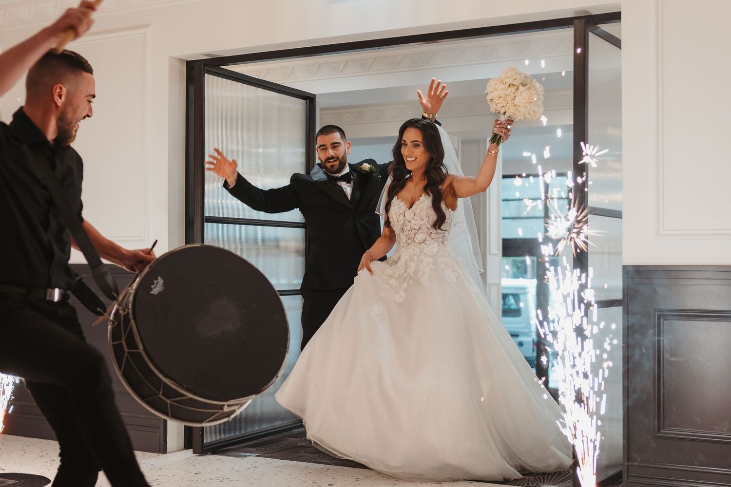A bride in a flowing white ballgown twirls gracefully during a wedding photoshoot in a bright indoor space.