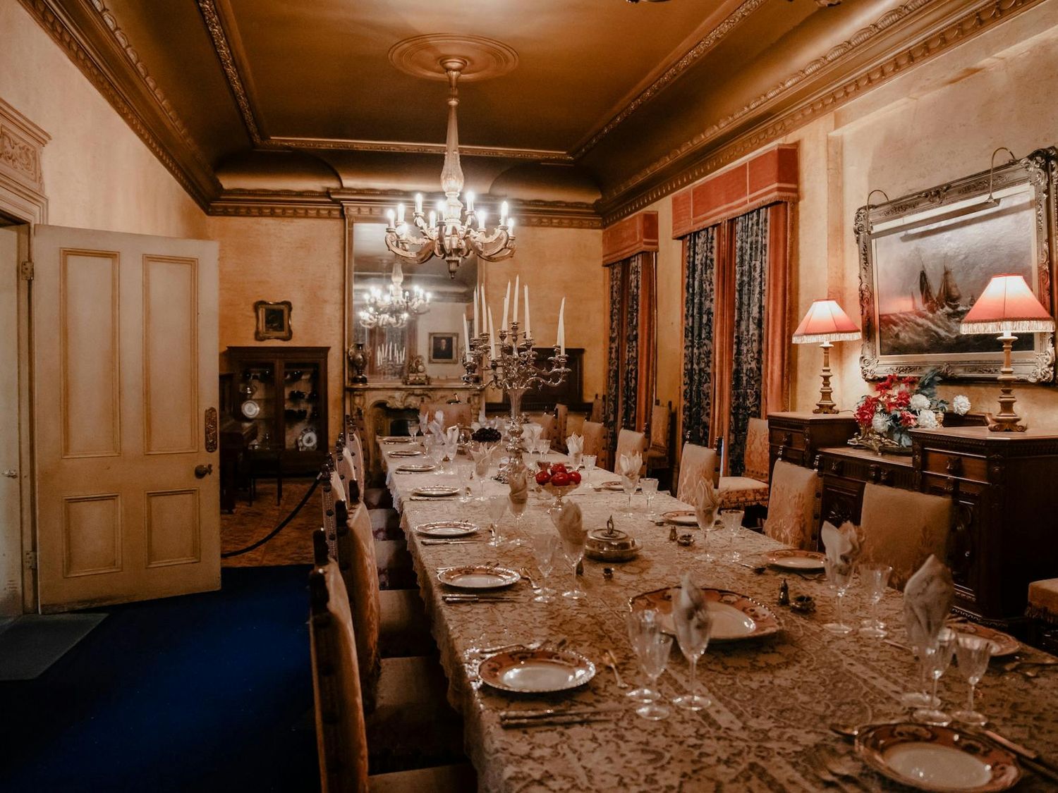 A luxurious vintage restaurant dining room with wood paneling, chandeliers and elegant table settings.