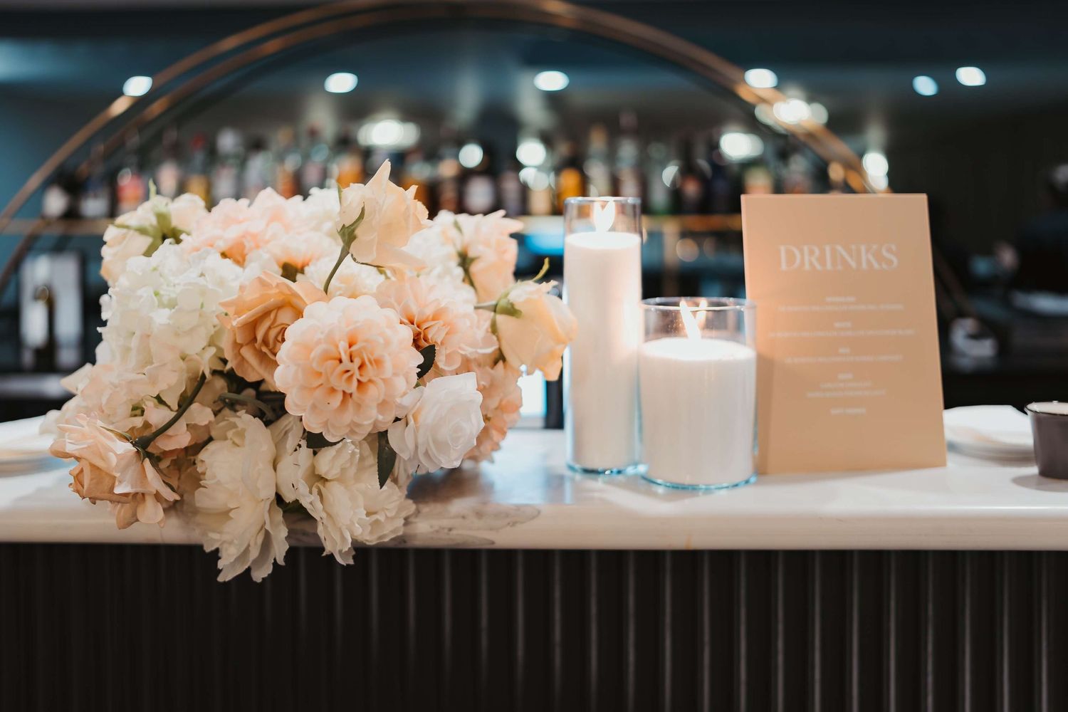 White and blush floral wedding centerpieces with glowing candles line an elegant reception table setup.