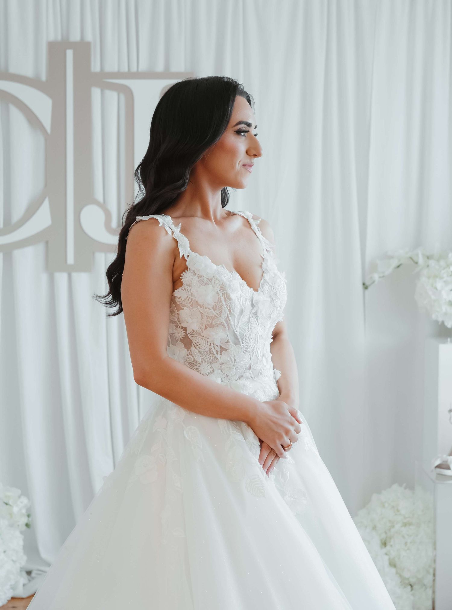Beautiful white wedding gown with delicate floral lace details and sweetheart neckline shown against light curtain backdrop.