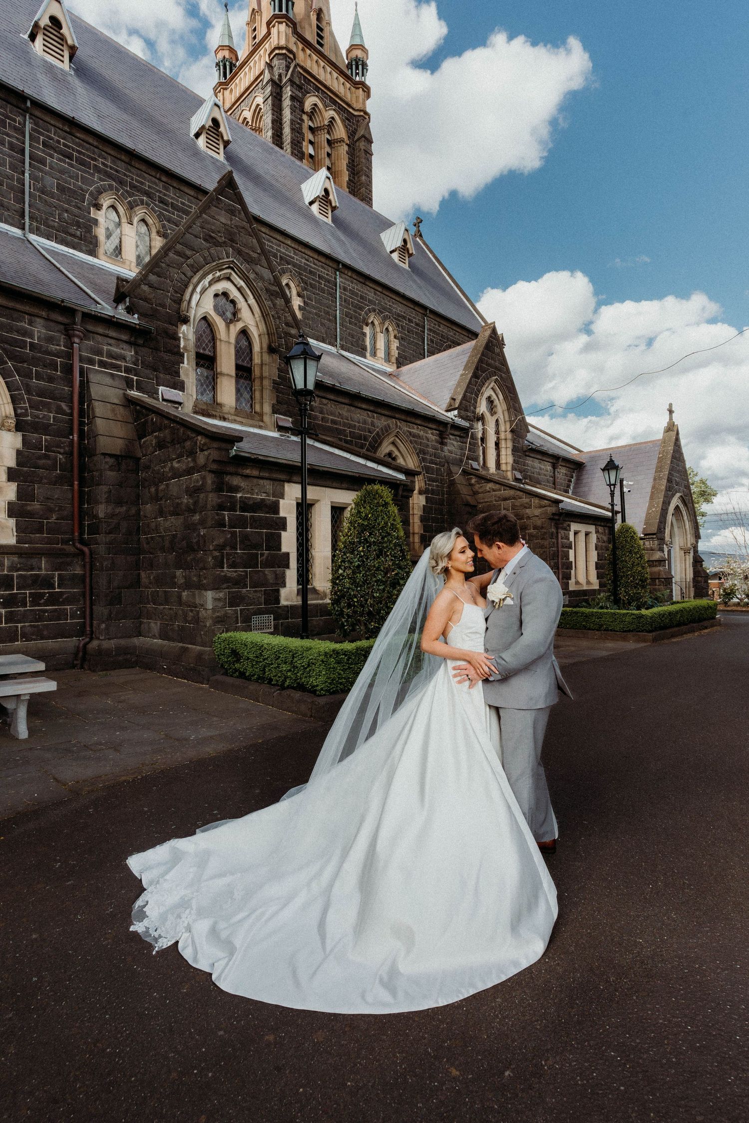 A romantic wedding couple shares intimate moments outside a gothic stone church on their special day.