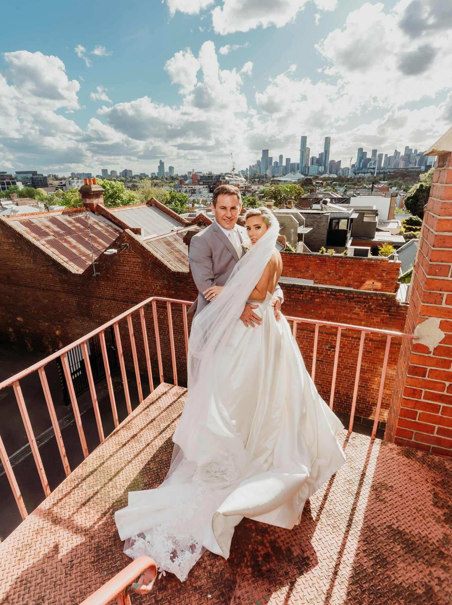 Couple shares romantic moments on a rooftop terrace overlooking the city skyline during a wedding photoshoot.