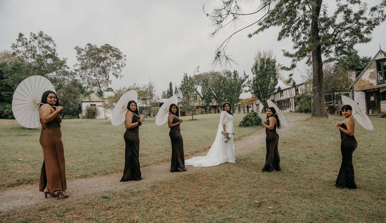 Bridal party walking single file through a grassy field creating a captivating diagonal line formation at sunset.