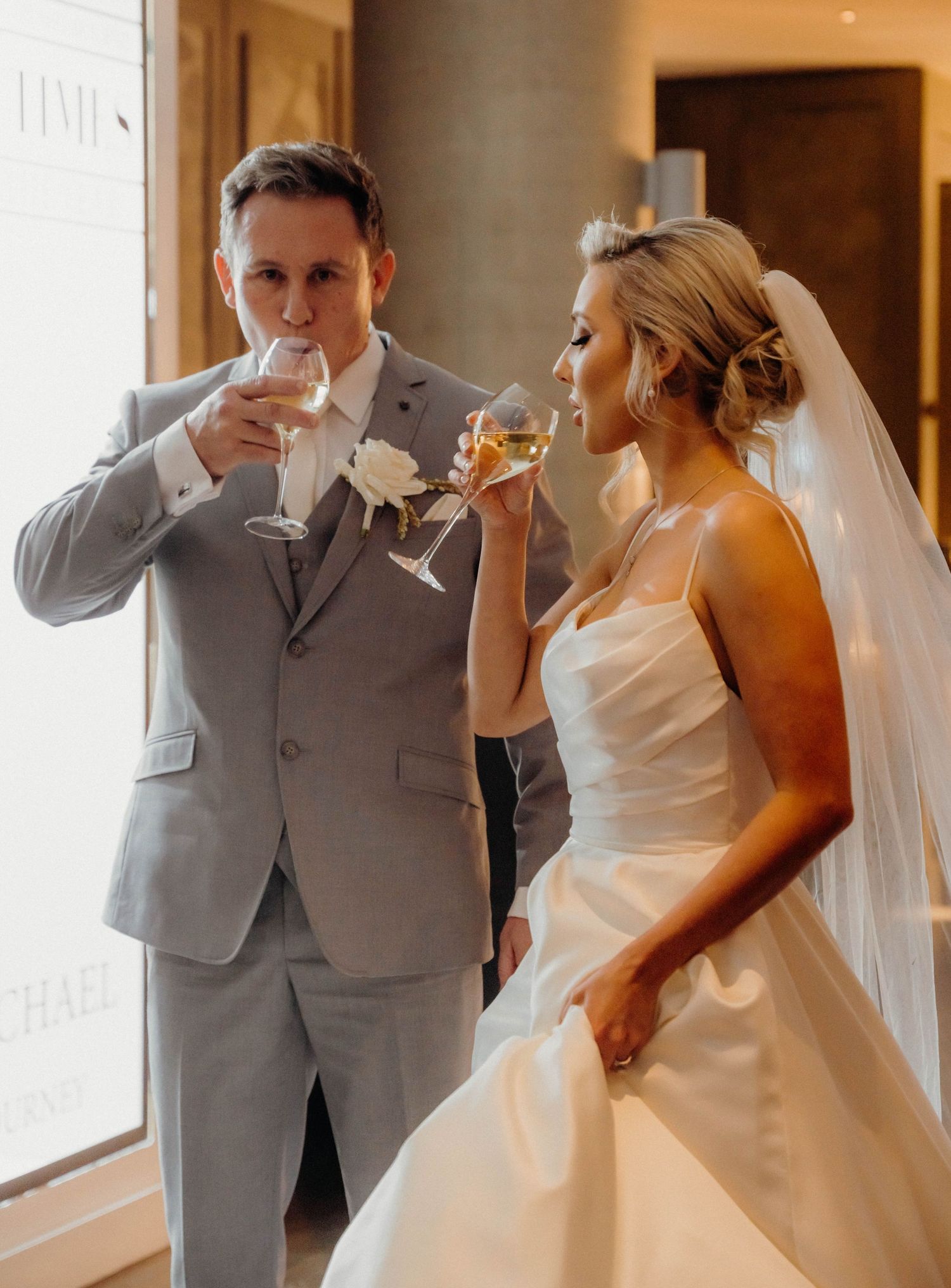 A wedding couple in white dress and gray suit take a series of celebratory shots together at their reception.