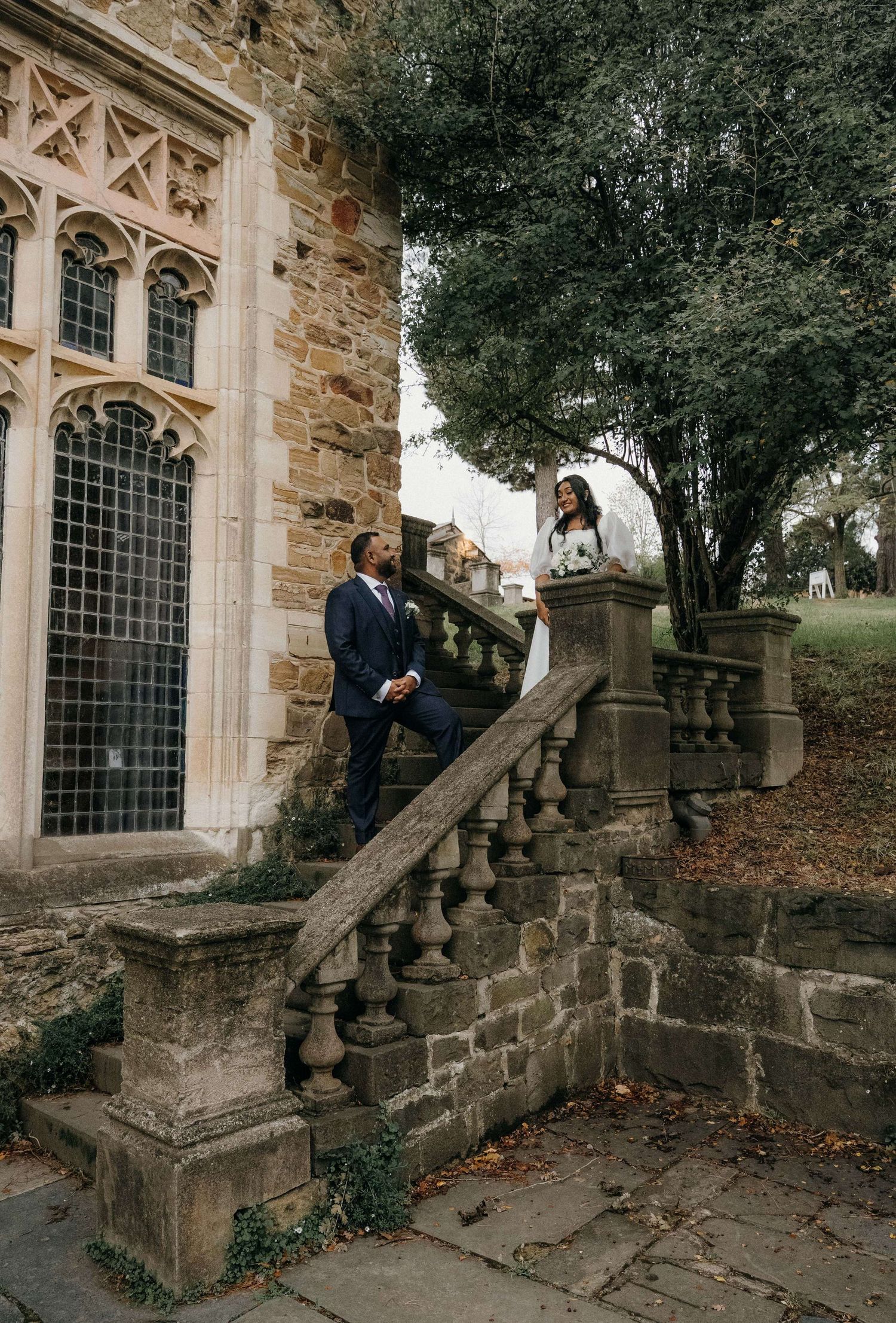 A gothic style stone church entrance with stairs and ornate architectural details surrounded by autumn foliage.