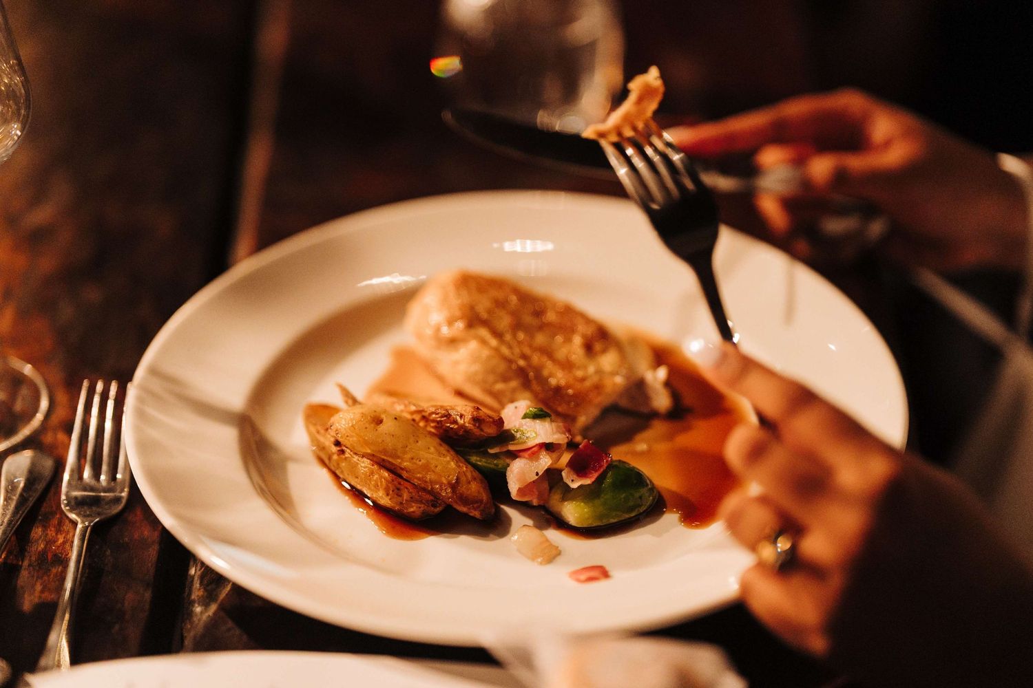 Elegant fine dining with white plates and glowing lights in a dark restaurant atmosphere.