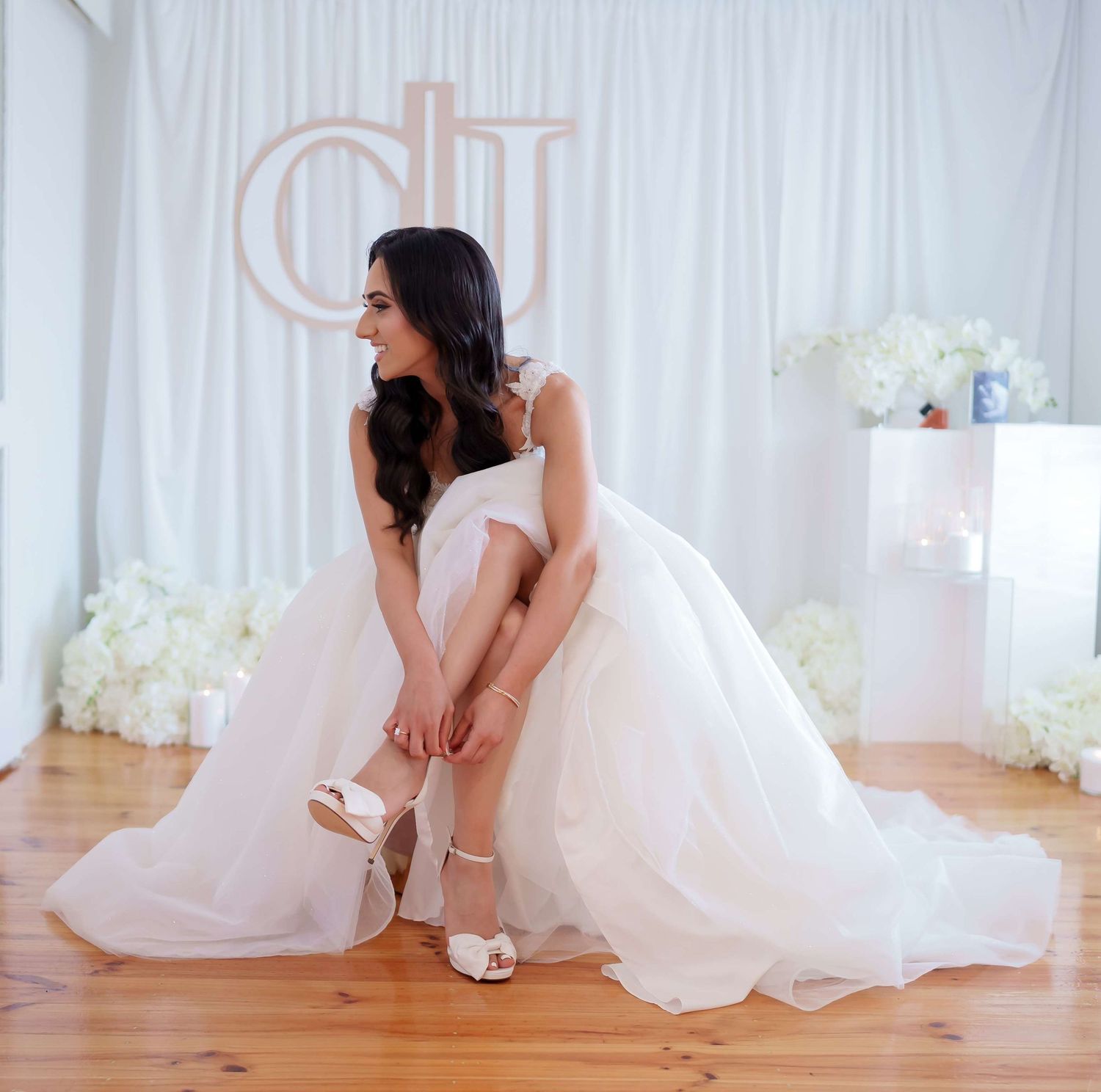 Four elegant bridal portraits showing a bride in a white gown sitting gracefully on a hardwood floor in a light-filled room.