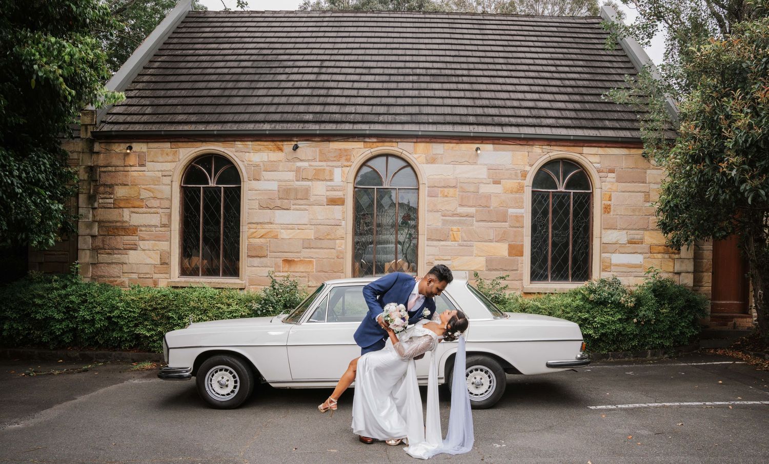 A panoramic collage of wedding moments at a rustic brick church venue with a classic car and garden setting.