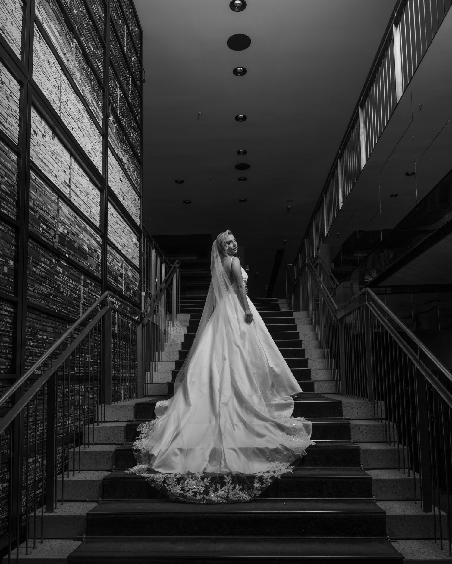 A dramatic black and white series showing a bride in a flowing wedding gown ascending a grand staircase.