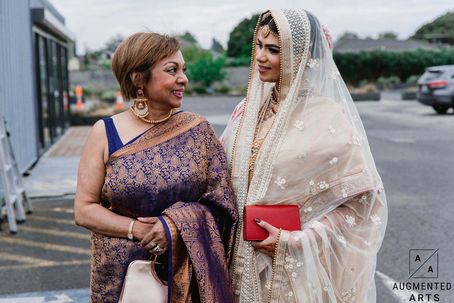 People in traditional Indian wedding attire gather outside for a celebratory photo session.