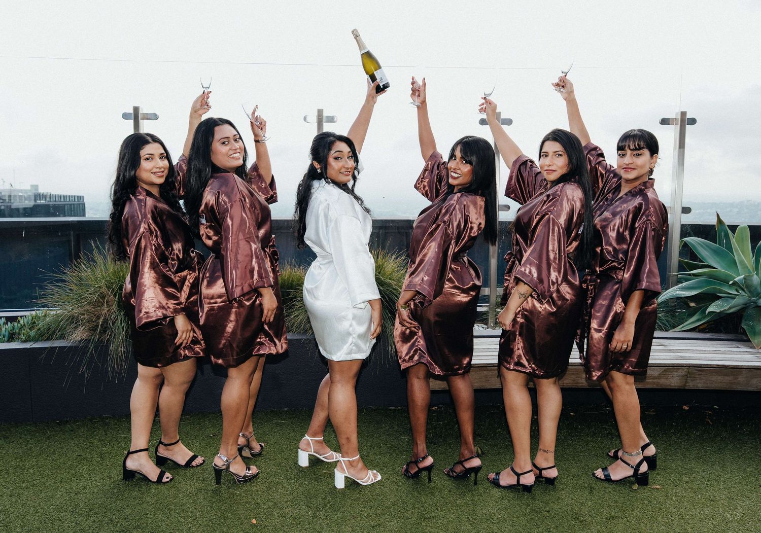A celebration sequence of multiple photos showing a group in matching outfits cheering and jumping together outdoors.