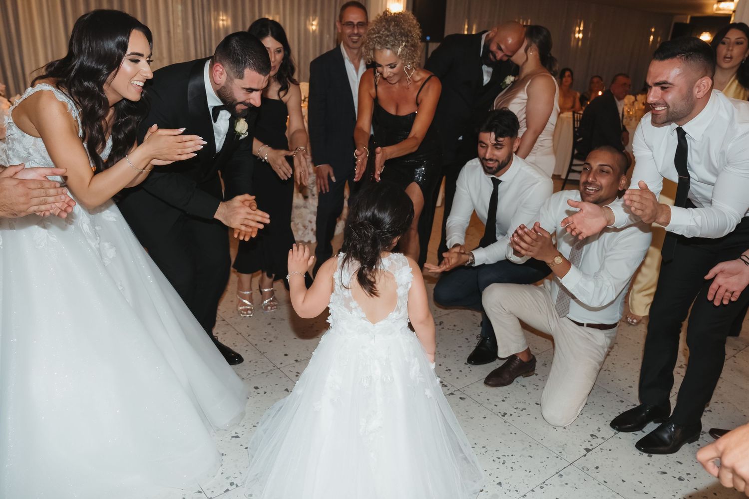 People form a circle around someone lying on the dance floor during a wedding reception celebration.