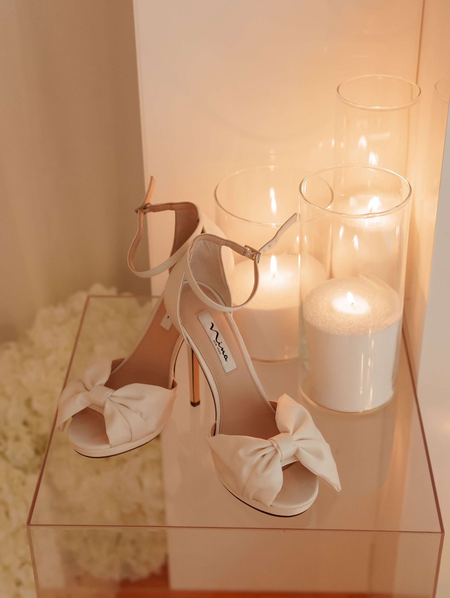 Three frosted glass candle holders with white candles create a soft, warm glow on a light-colored surface.