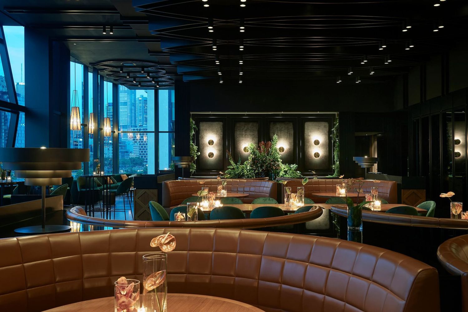 Modern restaurant interior with curved brown leather banquette seating and warm mood lighting creates an intimate atmosphere.