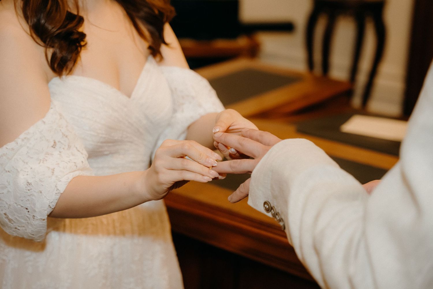 A couple signs wedding documents at a wooden table during their marriage ceremony.