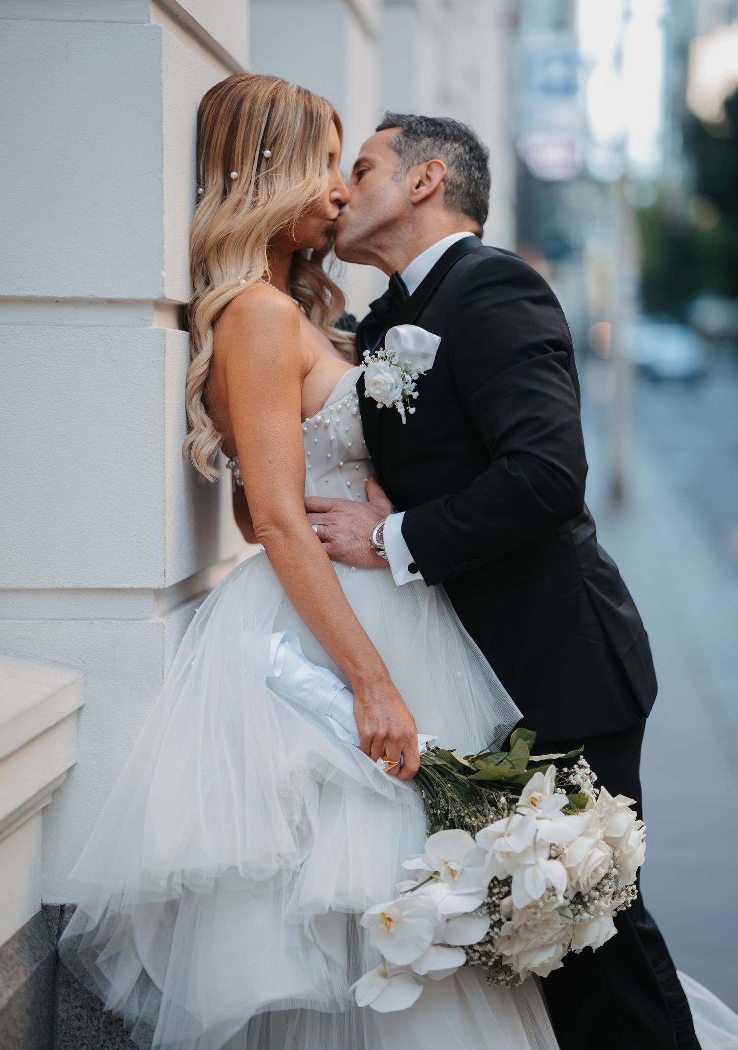 Romantic wedding couple shares intimate moments in a series of elegant outdoor portraits with white floral bouquet.