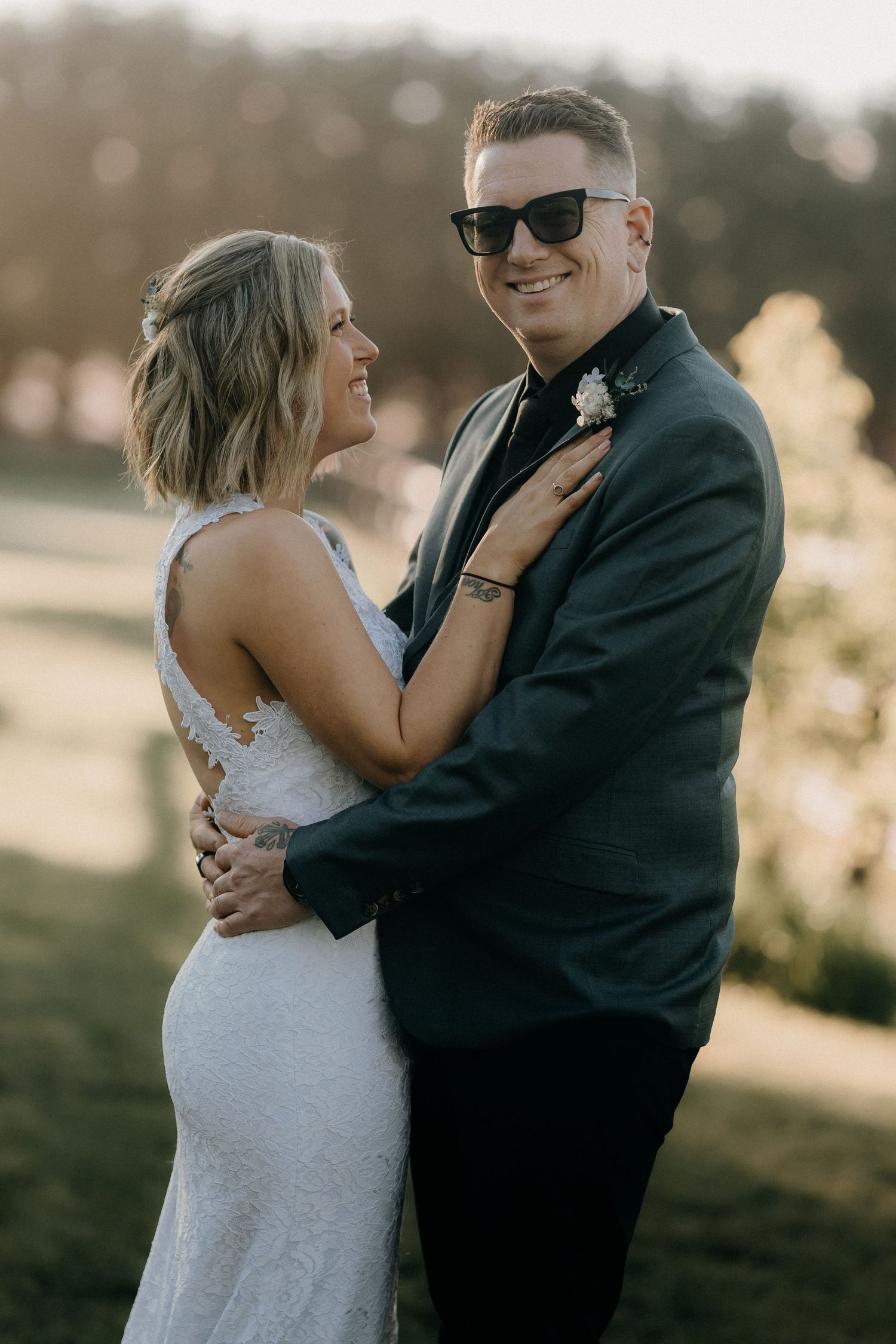 A couple in wedding attire share joyful moments during an outdoor sunset photoshoot.