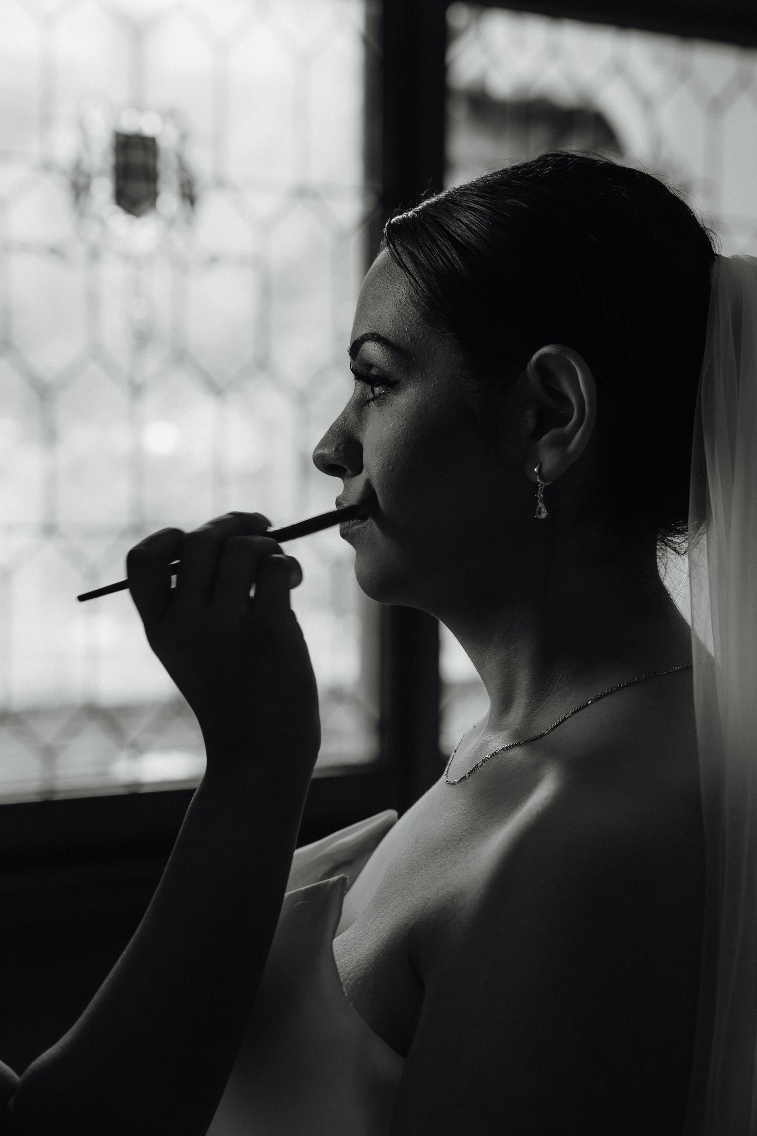 Black and white photo of a bride getting makeup applied before her wedding ceremony.