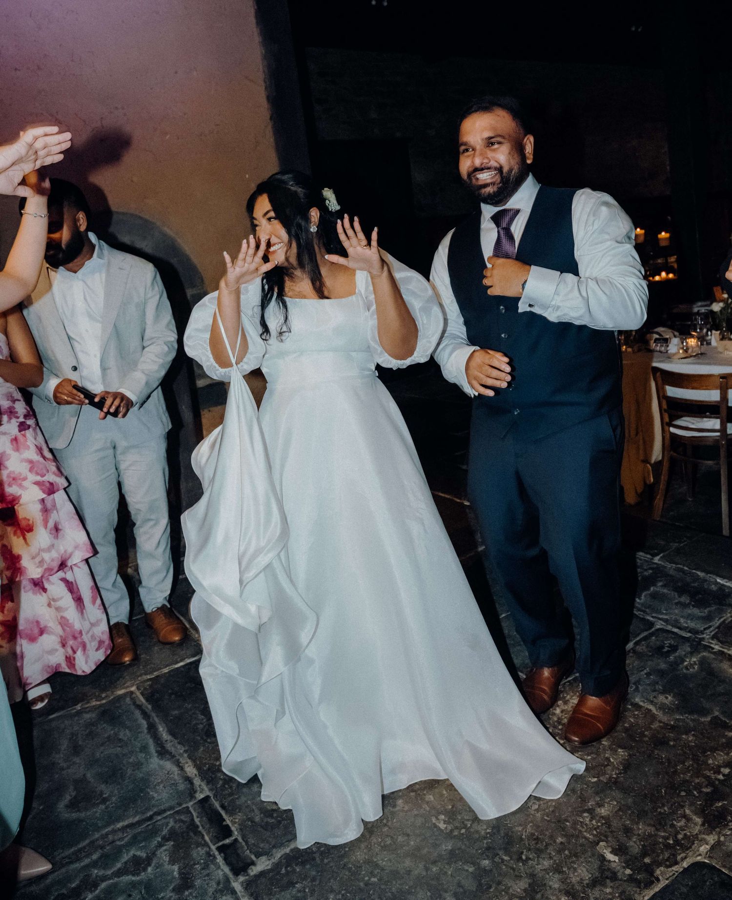 Wedding celebration with guests dancing and enjoying themselves on a stone floor during an evening reception.