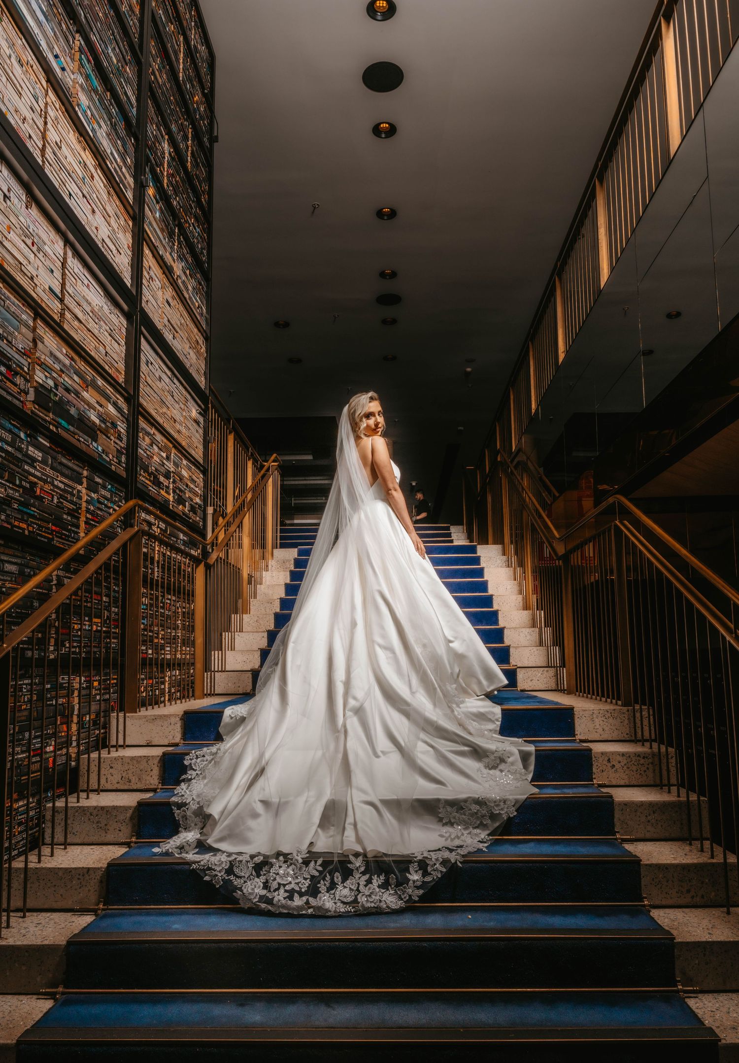 A wedding dress flows elegantly down navy blue carpeted stairs in a dramatic multi-frame sequence.