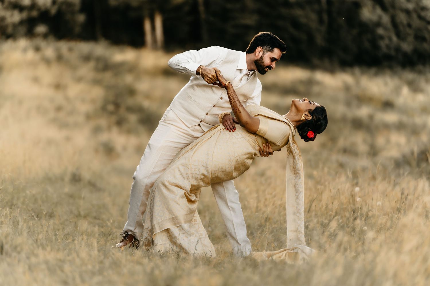 Cricket players in white uniforms play a match on a sunny field.