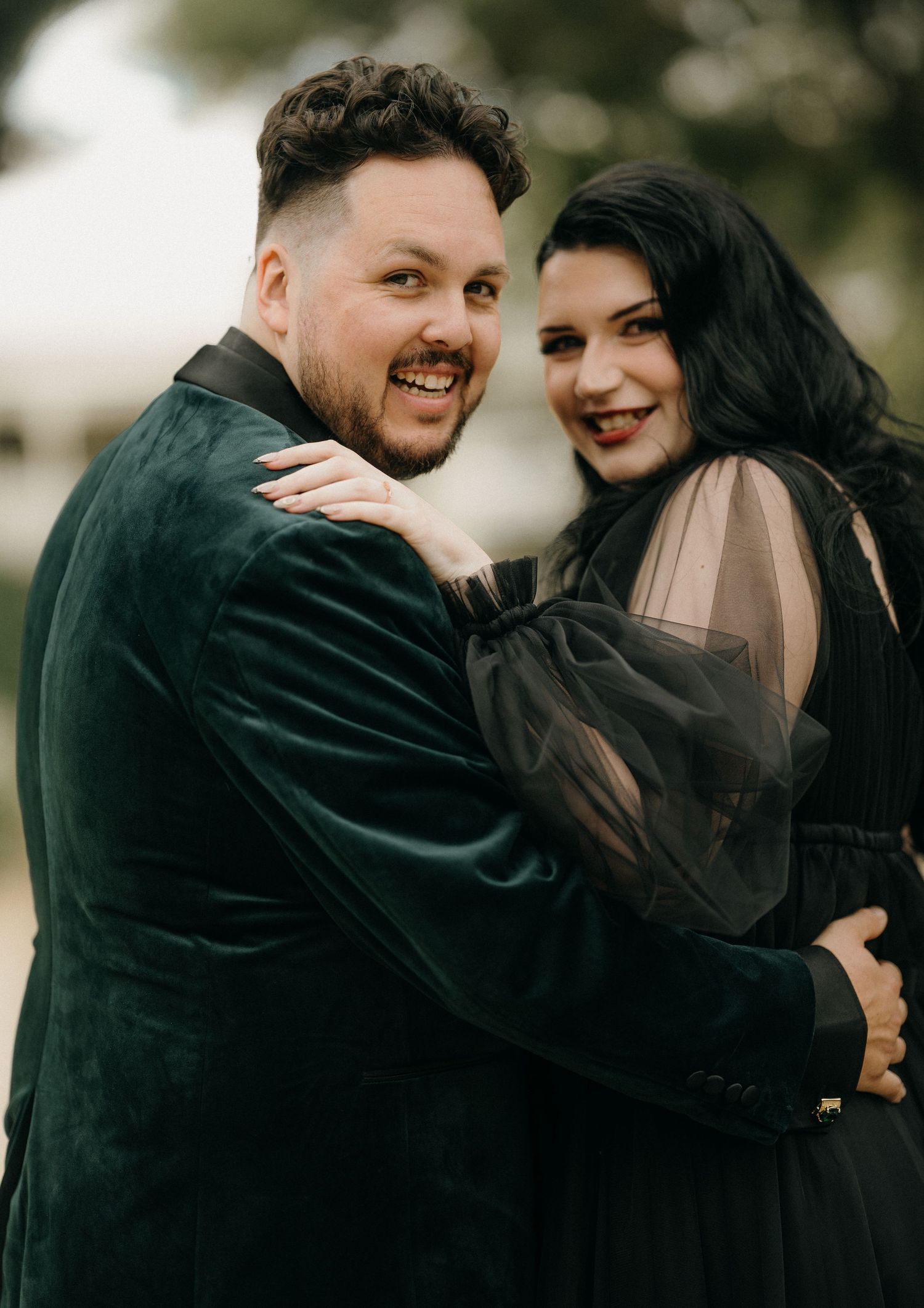 A couple shares intimate moments together while embracing and laughing in a romantic outdoor photoshoot.