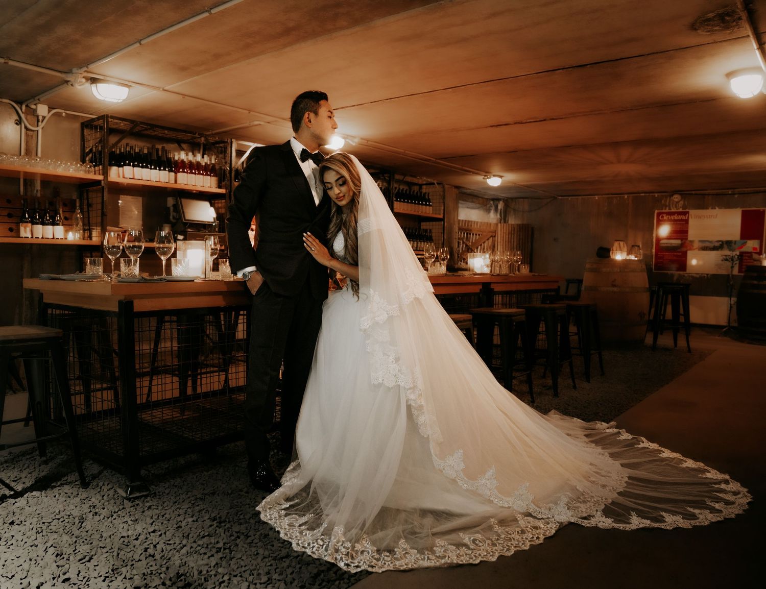 A romantic wedding photo captured in a rustic bar setting with wooden decor and warm lighting.