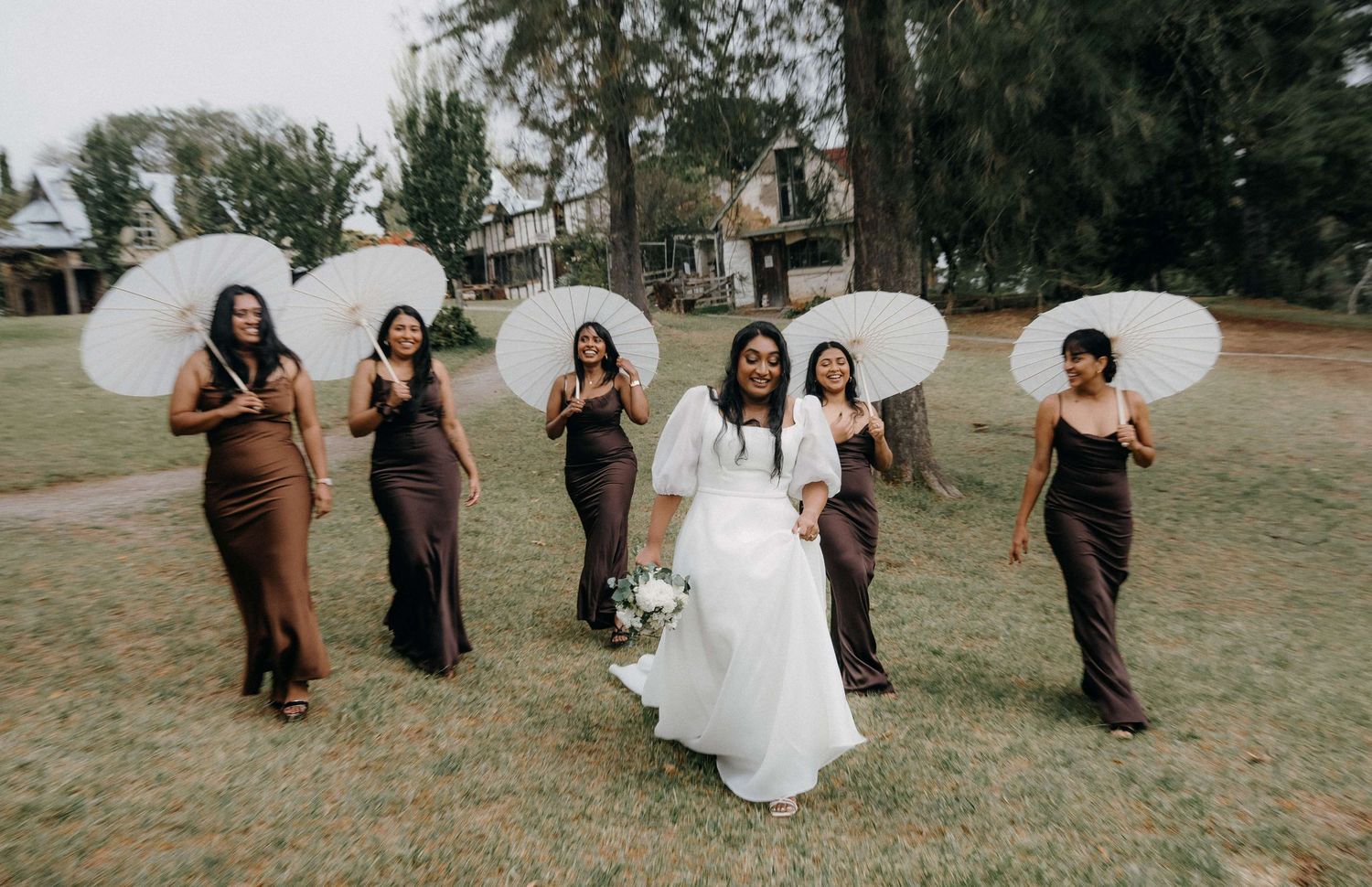A wedding party celebrates with joyful dance moves in a casual outdoor setting at golden hour.