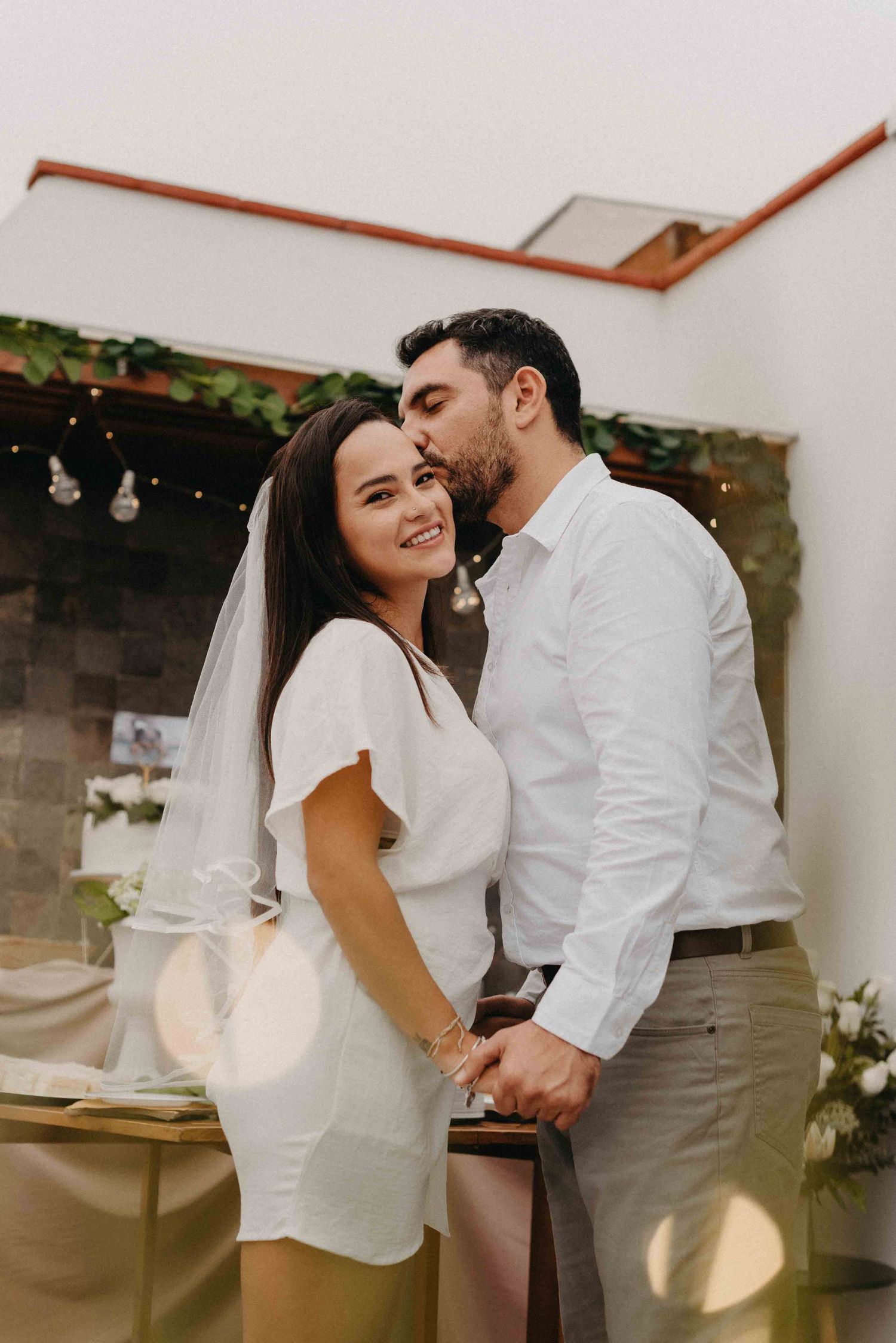 Intimate couple in white sharing a tender moment during their outdoor wedding celebration.