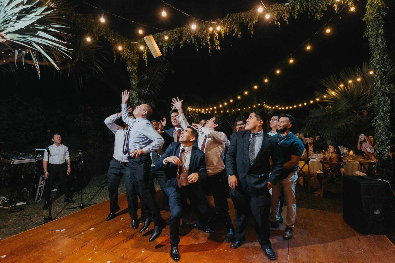 Wedding reception guests dancing under string lights at outdoor evening celebration.