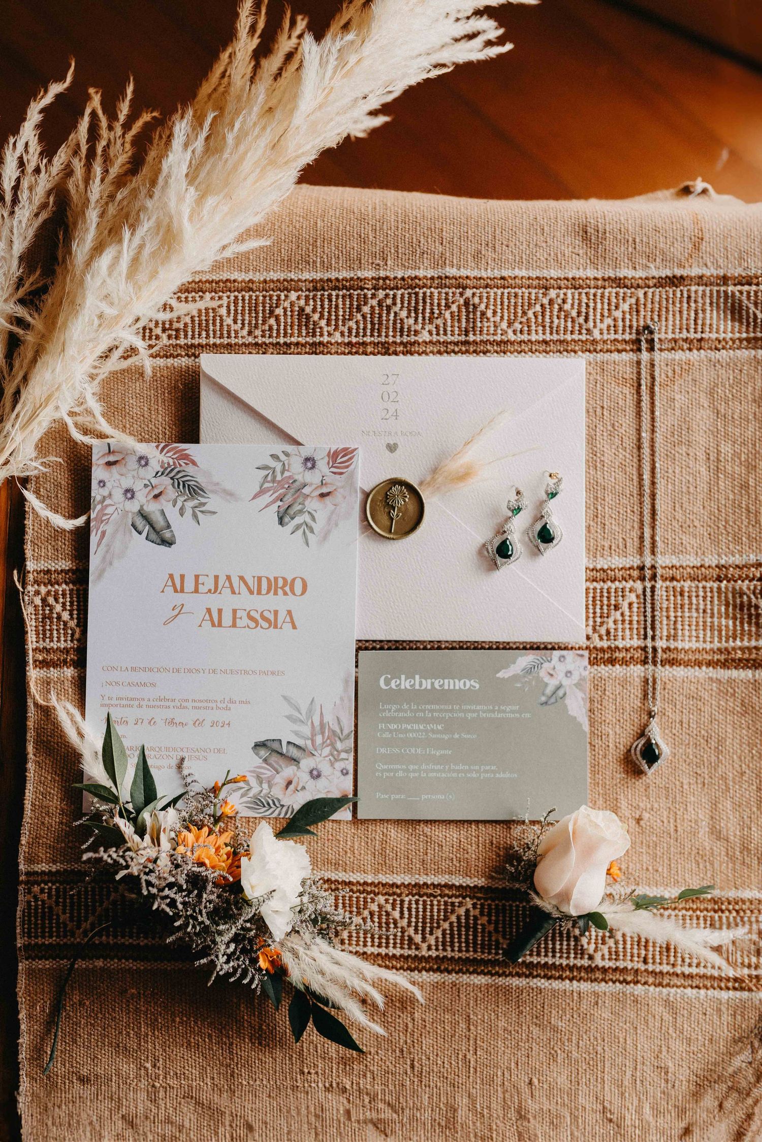 Elegant wedding invitation suite with floral design and pampas grass details on textured fabric.