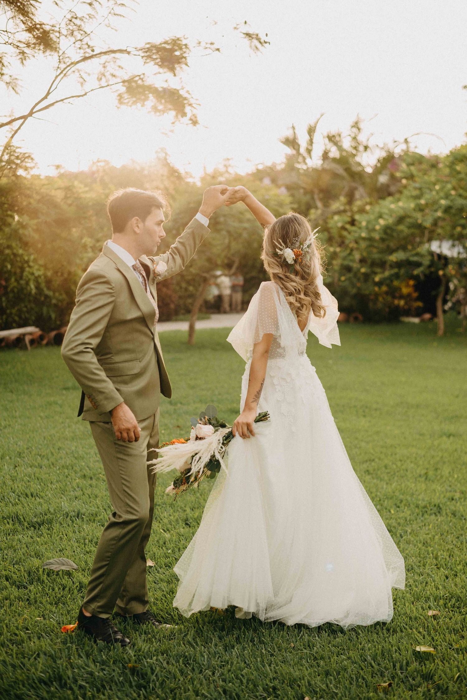 Couple dances together on a lawn during golden hour at their garden wedding.