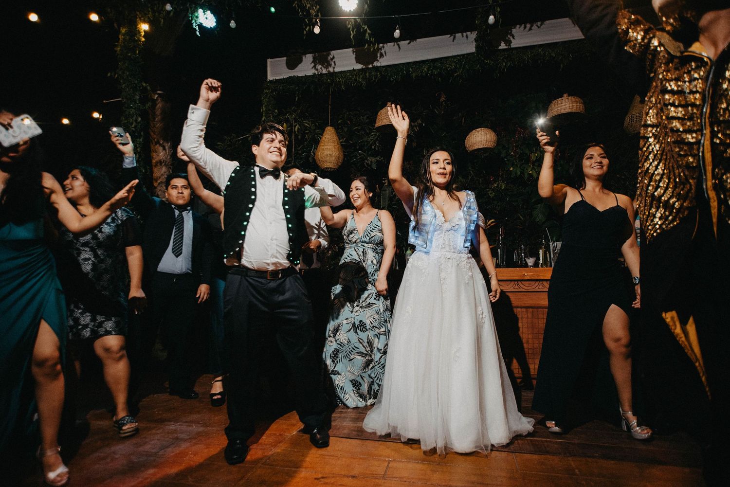 Wedding guests dancing and celebrating on an outdoor dance floor under string lights.