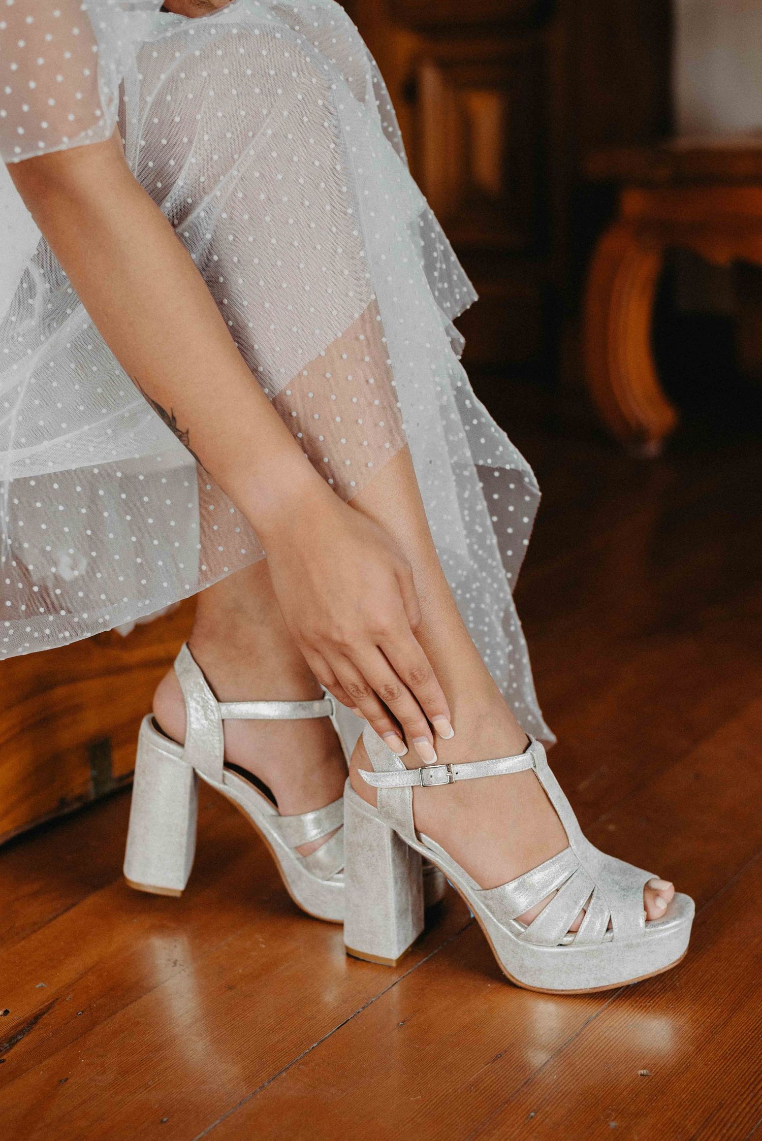 Close-up shots of bride putting on white polka dot wedding shoes with block heels.
