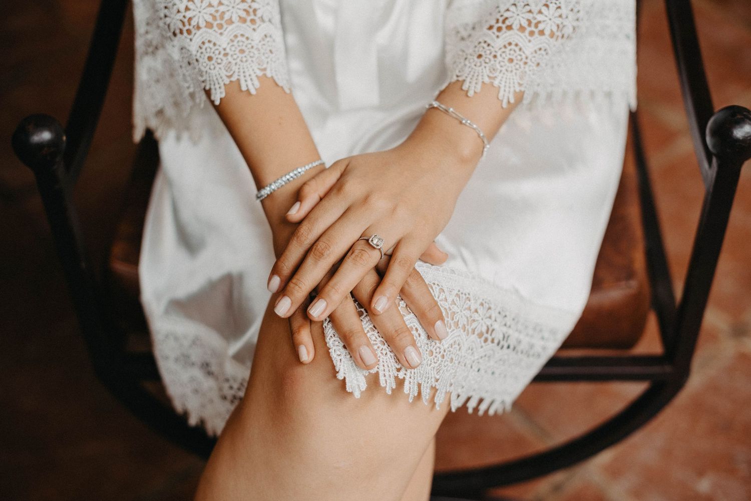 Close-up shots of bride's delicate white lace dress details and hands showing wedding day preparation moments.