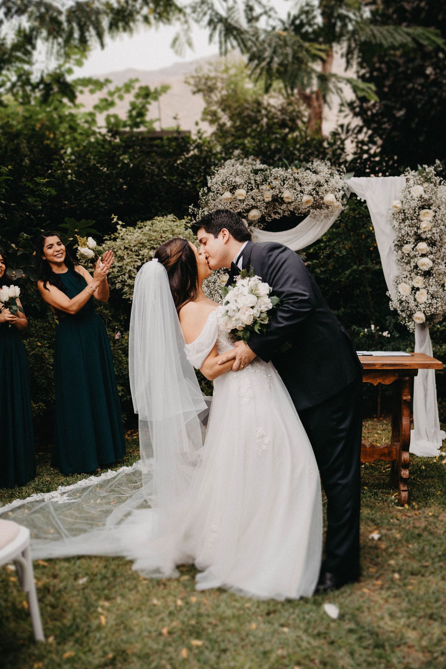 Elegant whimsical garden wedding ceremony with white floral arrangements and draped decor.