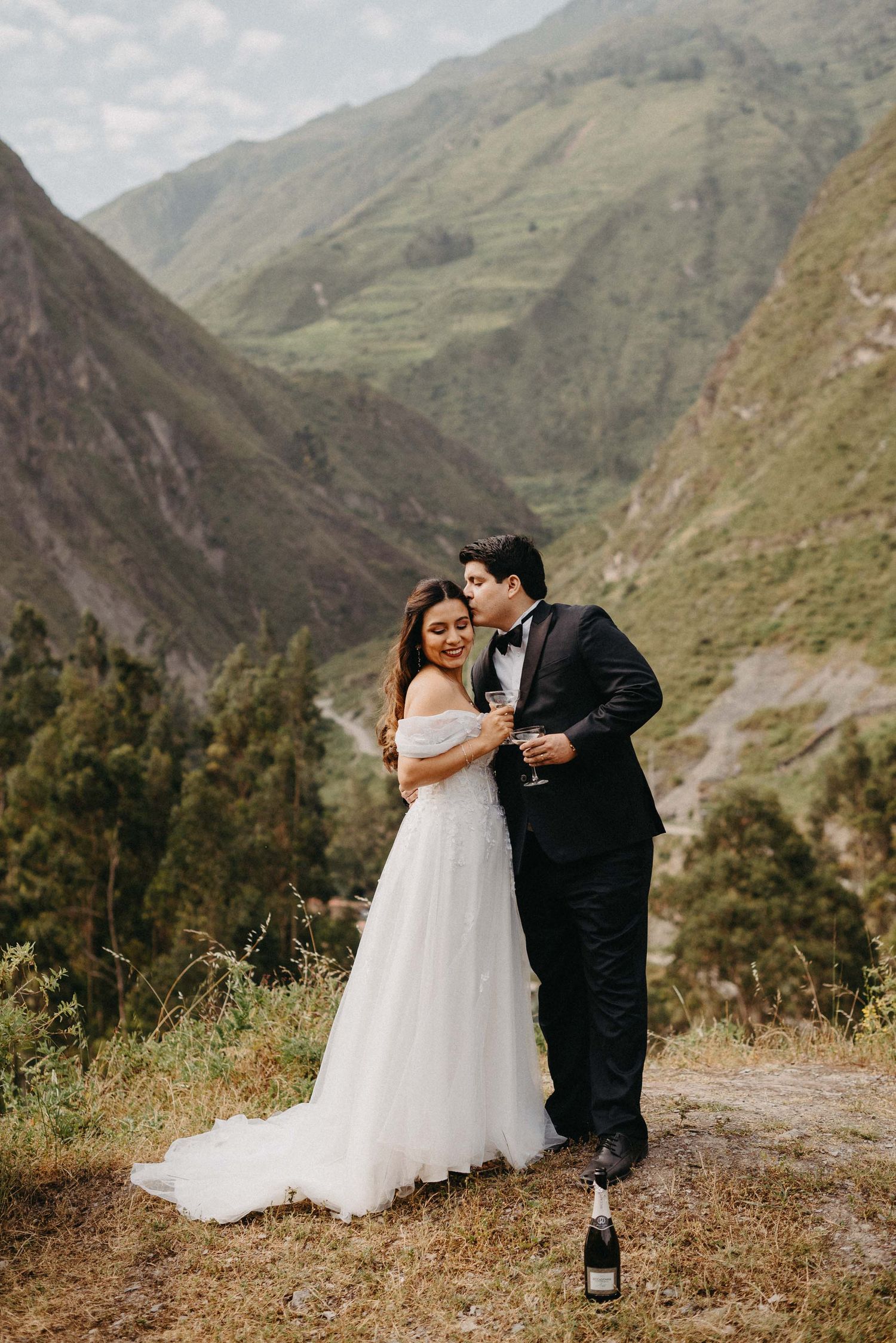 Wedding couple shares intimate moments against dramatic mountain landscape backdrop.