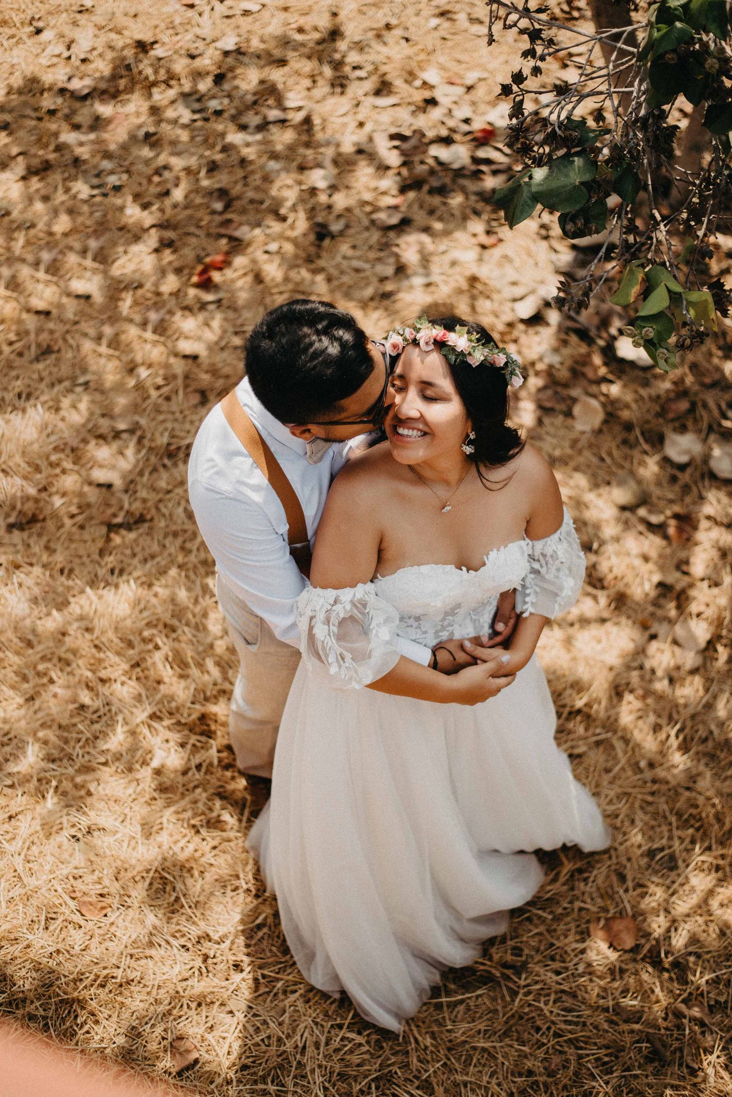 Golden sunlit wedding portraits of a couple embracing on dried grass.