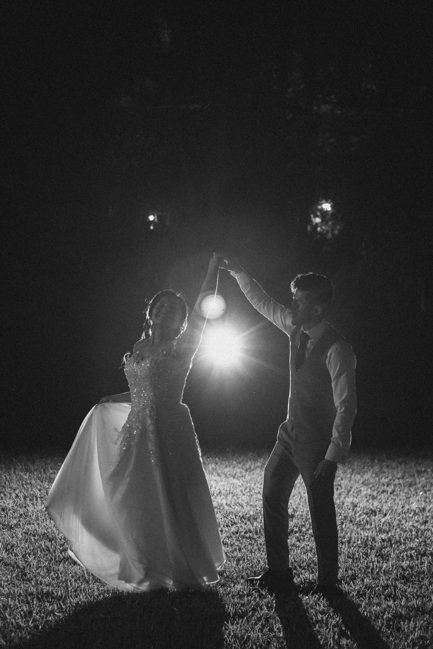 Silhouetted wedding couple dancing with lanterns creating magical nighttime atmosphere.