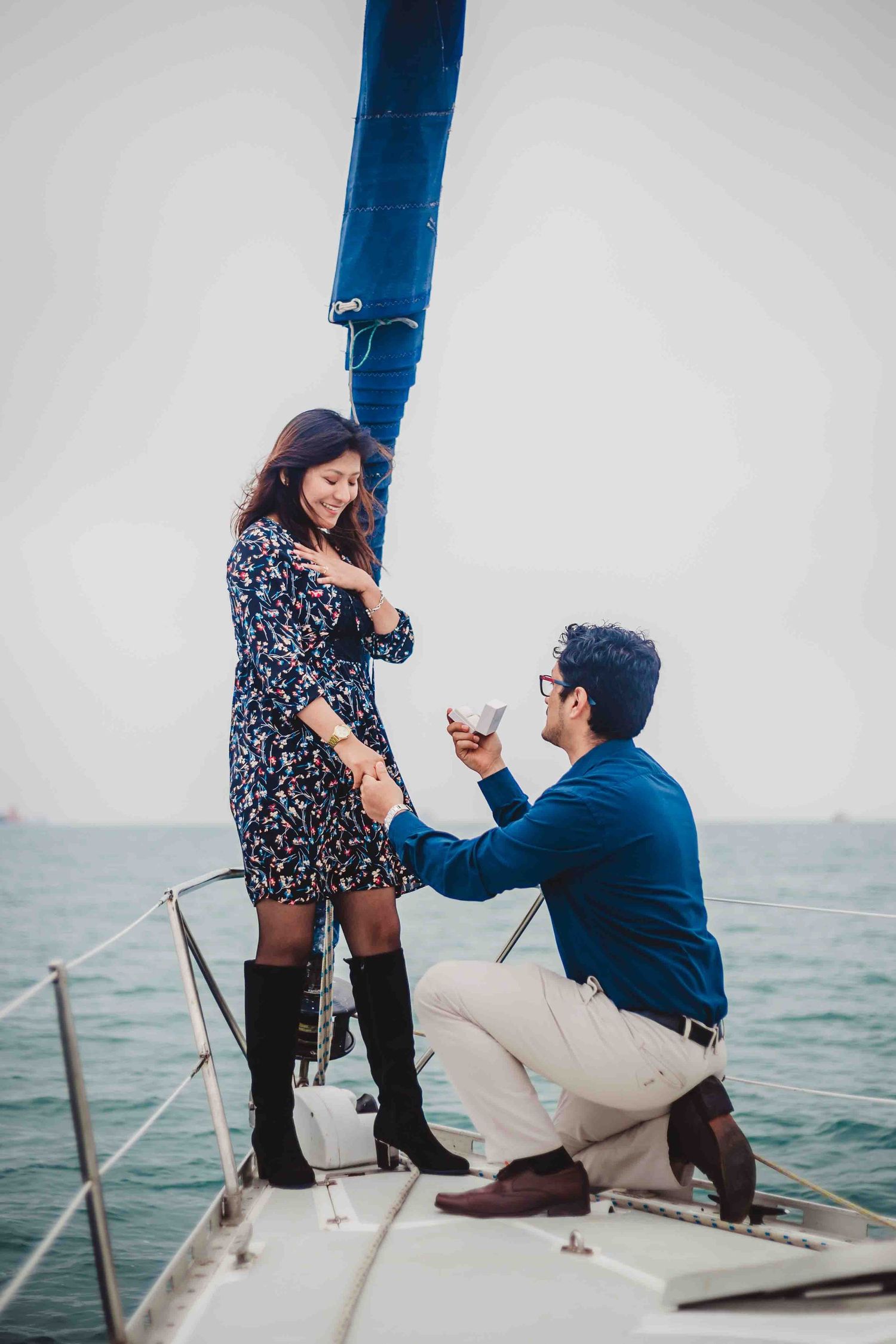Marriage proposal sequence on sailboat deck captures surprise engagement moment.