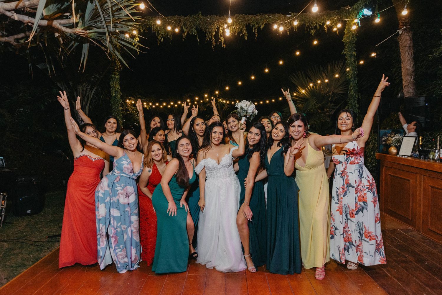 A series of wedding party photos showing people dancing and celebrating together under outdoor string lights at night.