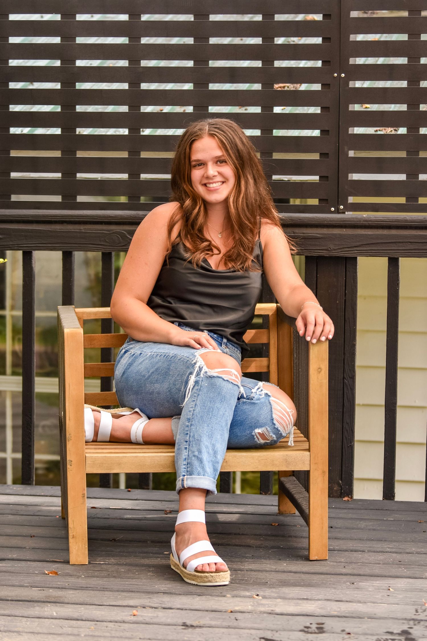 Relaxed portraits on wooden bench with slatted backdrop and natural lighting.