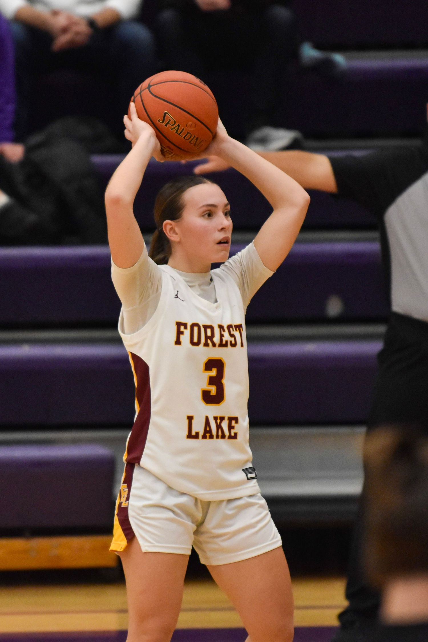 Basketball player in white Forest Lake uniform prepares to pass during game.