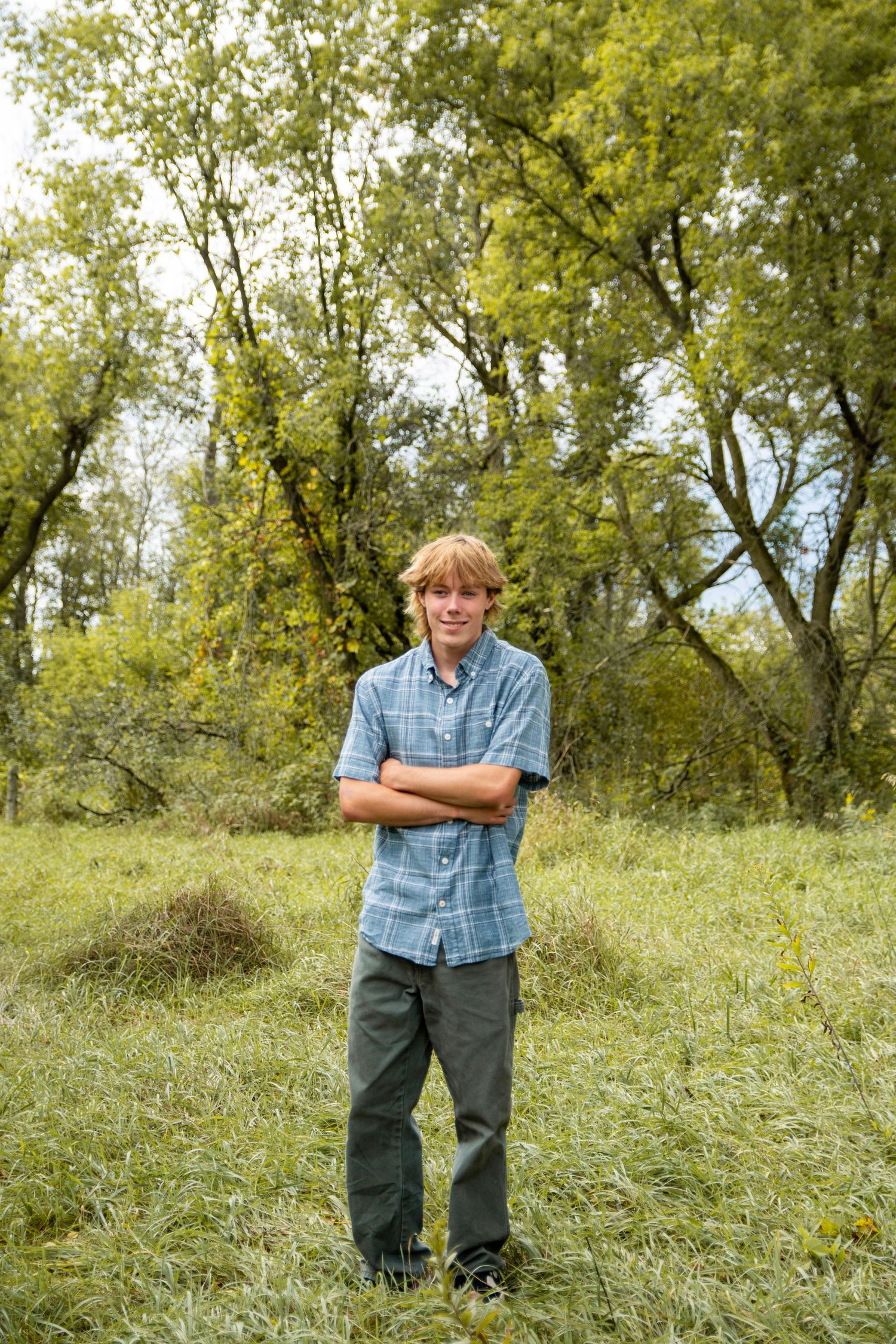Casual outdoor portrait session in a grassy field with trees in the background.