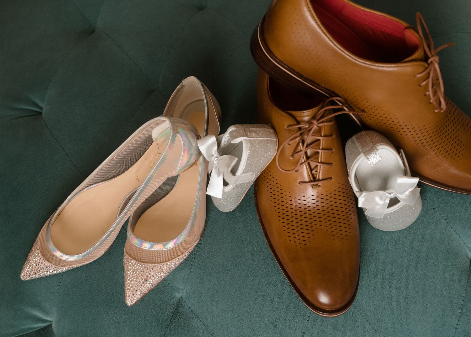 Brown leather dress shoes and beige pointed flats arranged on a green velvet surface.